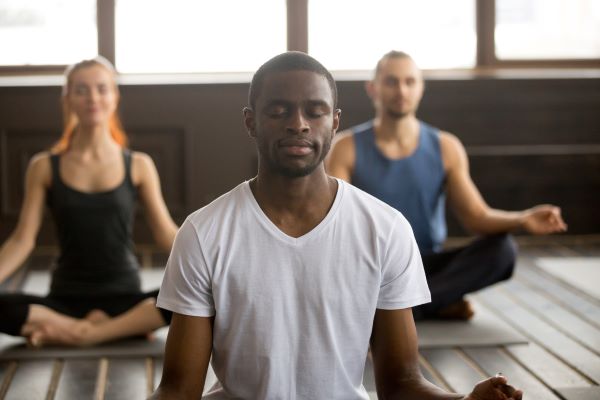 meditation_assise_collective Un groupe de personne sse tient assis les yeux fermés et médite